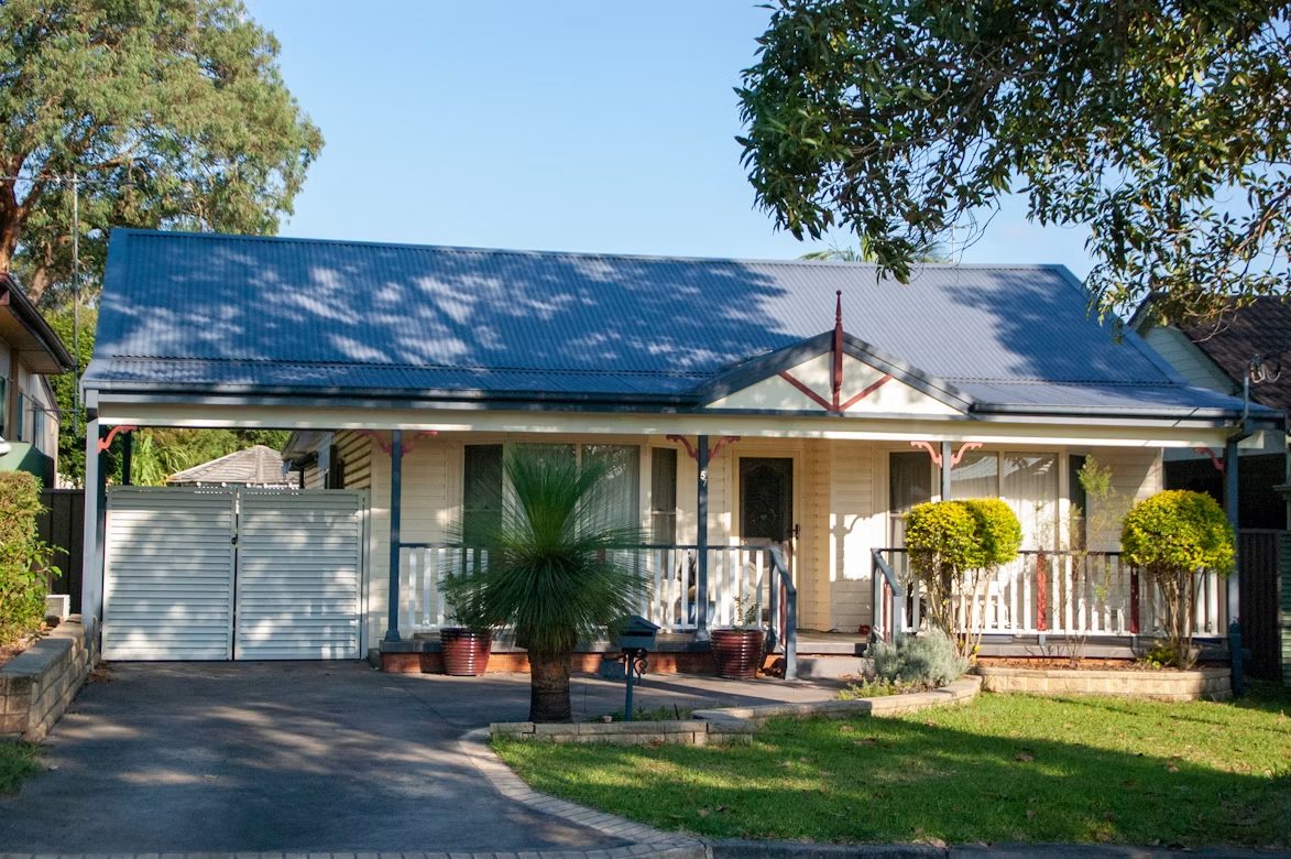 Fibro cottage with a blue corrugated roof and front verandah